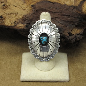 May include: A silver ring with a turquoise stone set in a scalloped design.