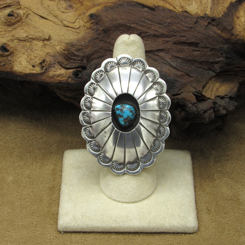 May include: A silver ring with a turquoise stone set in a scalloped design.