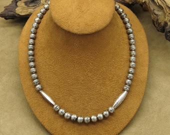 May include: A silver necklace with round beads and two silver bars at the ends.