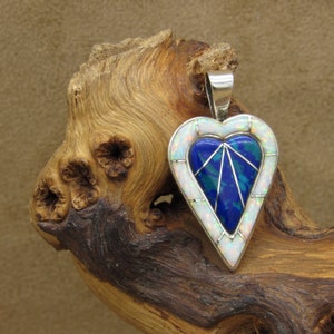 May include: A silver heart-shaped pendant with a blue and green inlay and white opal accents.