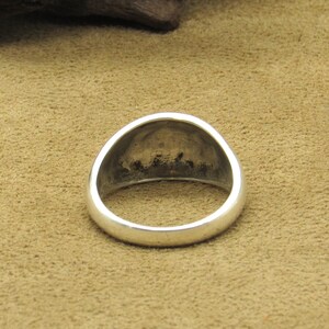 Peut inclure: Une bague en argent avec un dessus arrondi et bomb&eacute;. La bague a une finition lisse et polie et un design simple et classique. L'int&eacute;rieur de la bague pr&eacute;sente une d&eacute;coloration fonc&eacute;e. La bague est pos&eacute;e sur un fond beige.