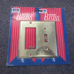 May include: A solid brass light switch cover plate with a single switch and outlet opening. The plate is packaged on a red, white, and blue striped backing with the word "Brass" printed on it. Includes mounting screws.