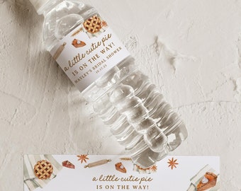Op de afbeelding: Waterfleslabel met een aquarel-illustratie van een taart en de tekst "a little cutie pie is on the way! Hayley's Bridal Shower 10.17.25".