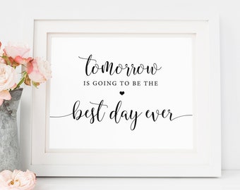 Puede incluir: Una impresión enmarcada en blanco con el texto "Tomorrow is going to be the best day ever" en escritura negra. A la izquierda de la impresión hay una jarra de metal galvanizado con rosas rosas.