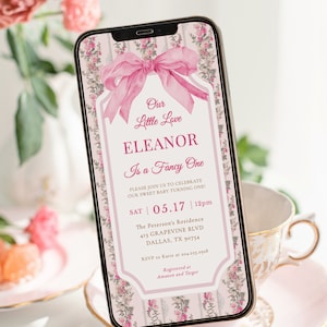 May include: A pink and white digital invitation for a baby's first birthday party. The invitation features a pink bow, floral patterns, and the text "Our Little Love Eleanor Is a Fancy One". The invitation includes the date and time of the party, the location, and RSVP information. It also states that gifts can be registered at Amazon and Target.