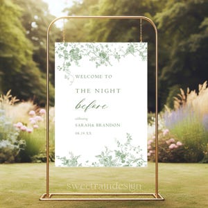 May include: A gold metal wedding sign with a white background and green floral design. The sign reads "Welcome to The Night Before" and celebrates Sarah & Brandon. The sign is displayed outdoors.