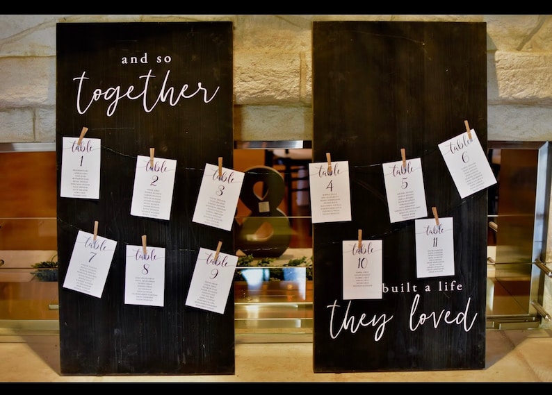 Puede incluir: Dos letreros de madera negra con caligraf&iacute;a blanca. El letrero de la izquierda dice "and so together" y tiene n&uacute;meros de mesa del 1 al 9 colgando de &eacute;l. El letrero de la derecha dice "built a life they loved" y tiene n&uacute;meros de mesa del 4 al 6 y del 10 al 11 colgando de &eacute;l.