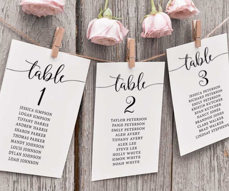 Puede incluir: Tres tarjetas blancas con caligraf&iacute;a negra que dice "mesa 1", "mesa 2" y "mesa 3". Cada tarjeta enumera nombres para un diagrama de asientos de recepci&oacute;n de boda.