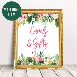 May include: A gold framed sign with a white background and pink text that says "Cards & Gifts". The sign is decorated with tropical leaves and flowers, including a pink flamingo.