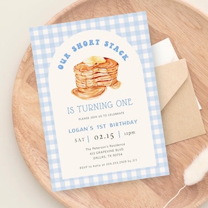 Puede incluir: Una invitación de fiesta de primer cumpleaños con un patrón de cuadros azules y blancos. La invitación presenta una ilustración de acuarela de una pila de panqueques con mantequilla y jarabe. El texto de la invitación dice: "Our Short Stack is Turning One. Please join us to celebrate Logan's 1st Birthday. Sat 02.15 12pm. The Peterson's Residence 413 Grapevine Blvd Dallas, TX 90754. RSVP to Katie at 204.253.2928 by 2/1."