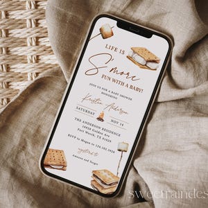 Könnte beinhalten: Ein Smartphone zeigt eine Babyparty-Einladung mit S'mores-Thema. Die Einladung enthält Aquarellillustrationen von S'mores und Marshmallows. Der Text lautet "Life is S'more Fun with a Baby!" und enthält Veranstaltungsdetails.