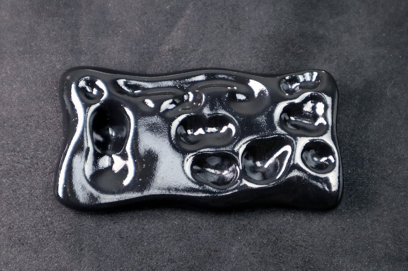 May include: Black ceramic paint palette with multiple circular wells for mixing paint.