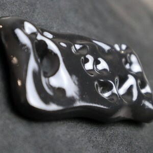 May include: A black ceramic ornament with a smooth, glossy finish and an abstract, organic shape.