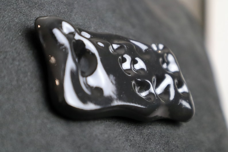 May include: A black ceramic ornament with a smooth, glossy finish and an abstract, organic shape.