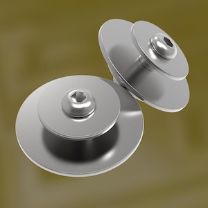 Op de afbeelding: Twee zilveren metalen schroeven met een platte, cirkelvormige basis en een kleinere, verhoogde bovenkant. De bovenkant van elke schroef heeft een zeskantige aansluiting voor een inbussleutel. De schroeven staan tegen een gedempte, olijfkleurige achtergrond.