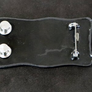 May include: Black enamel pin with two silver metal posts on the back and a silver metal pin back.