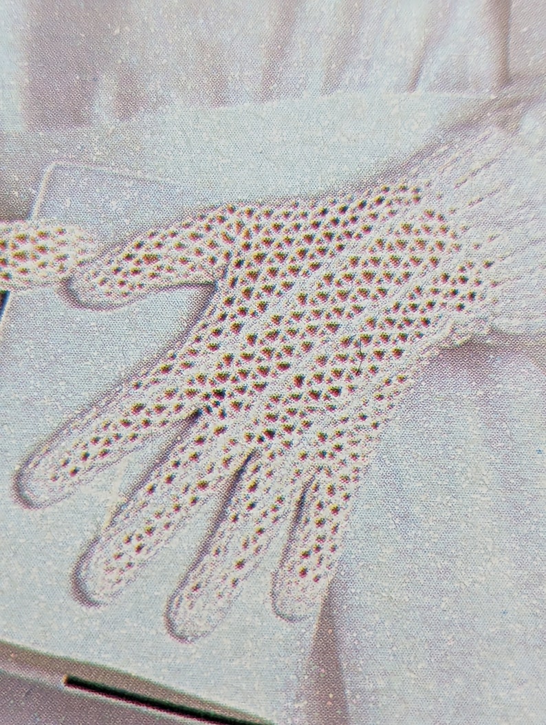 May include: A white crocheted glove with a delicate pattern. The glove is made with a fine yarn and has a delicate, feminine look.