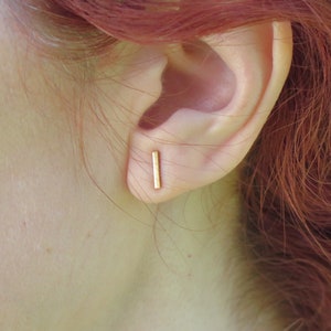 May include: A pair of gold bar stud earrings. The earrings are simple and minimalist, and they are perfect for everyday wear.