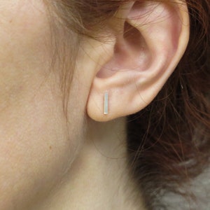 May include: A pair of silver bar stud earrings. The earrings are simple and minimalist, and they are perfect for everyday wear.