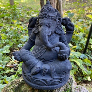 May include: Black stone statue of Ganesha, the Hindu god of wisdom and prosperity, sitting in a meditative pose with his trunk curled up. The statue is intricately detailed and has a traditional headdress.