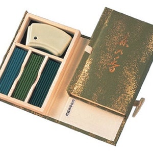 May include: A wooden box with a green lid containing incense sticks and a ceramic incense holder. The lid has gold lettering that reads "香りの贈り物".