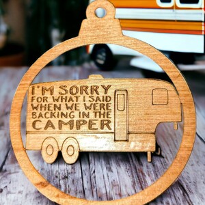 May include: A wooden Christmas ornament shaped like a camper with the text "I'm sorry for what I said when we were backing in the camper".