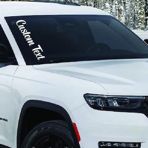 May include: White Jeep Grand Cherokee with a windshield decal that says "Custom Text".