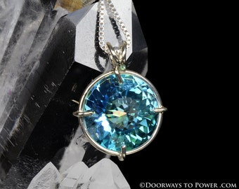 May include: A round blue topaz gemstone pendant with a silver chain and a silver setting. The pendant is set against a background of clear quartz crystals.