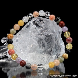 Puede incluir: Un brazalete de cuentas de colores con una variedad de piedras, incluyendo cuarzo transparente, jaspe rojo, citrino amarillo y amatista. El brazalete está hecho con cuentas de 8 mm y tiene una longitud aproximada de 18 cm.