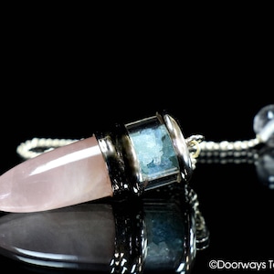 May include: A rose quartz pendulum with a silver chain and a clear quartz crystal at the end. The pendulum is filled with aquamarine crystals.