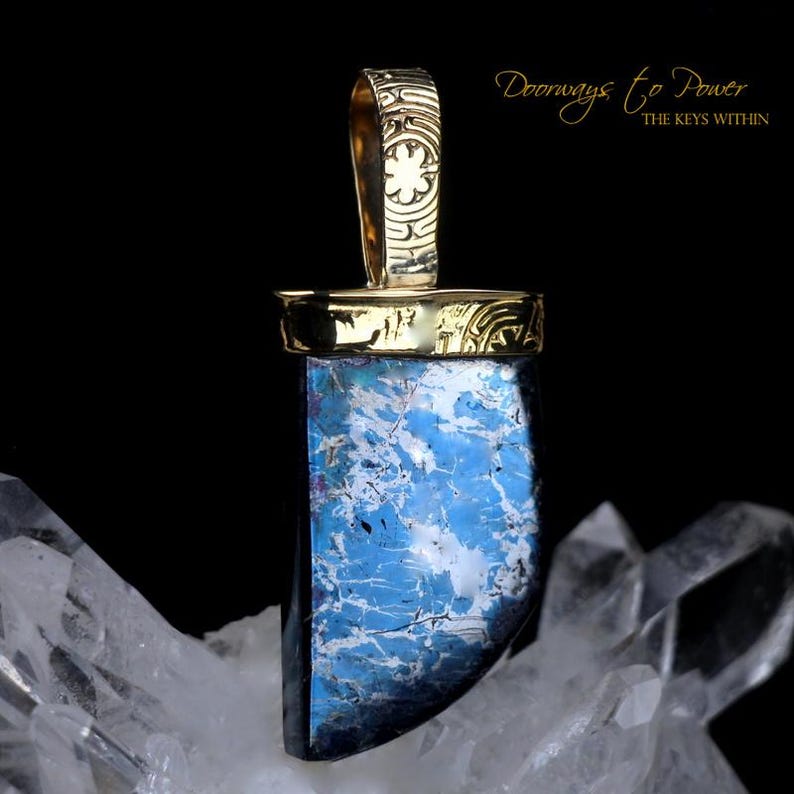 Pu&ograve; includere: Un ciondolo d'oro con una pietra blu e bianca. La pietra &egrave; incastonata in una ghiera d'oro e il ciondolo ha un'anellina d'oro. Il ciondolo &egrave; su uno sfondo bianco.