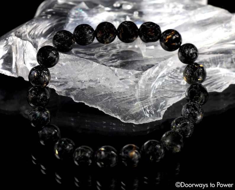 May include: Black obsidian bracelet with gold flecks. The bracelet is made of round beads and is strung on elastic.
