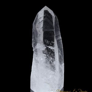 May include: A clear quartz crystal point with a faceted tip. The crystal is transparent with internal inclusions and sits against a black background. The base is a rough, natural shape. The text "Doorways to Power" is visible at the bottom.