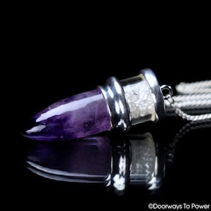 Op de afbeelding: Amethyst kristallen punt hanger met een heldere glazen flesje gevuld met kleine witte kristallen. De hanger is bevestigd aan een zilveren ketting.