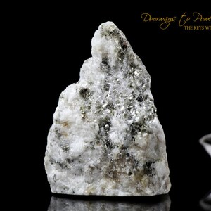 Könnte beinhalten: Ein rauer, weißer und grüner Kristall mit einer strukturierten Oberfläche. Der Kristall ist in Form eines kleinen Berges und hat ein natürliches, rohes Aussehen.