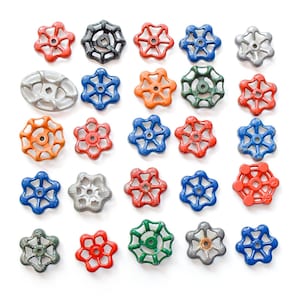 May include: A collection of colorful, vintage-style valve handles in various colors, including red, blue, orange, green, gray, and black. The handles are arranged on a white background, showcasing their star-shaped designs.
