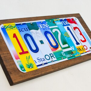 Puede incluir: Una placa de madera con la fecha 10-02-13 escrita con placas de matr&iacute;cula de diferentes estados. Los n&uacute;meros son rojos, azules y verdes. La placa es una excelente manera de conmemorar una fecha especial.