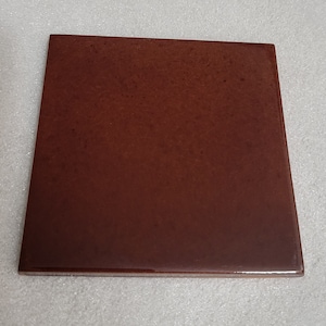 May include: A square, brown ceramic tile with a smooth, glossy finish.