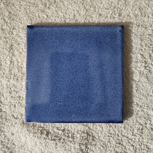 May include: A solid blue ceramic tile with a slightly textured surface.