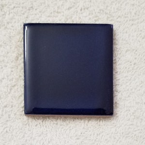 May include: A single, solid blue ceramic tile. The tile is smooth and glossy.