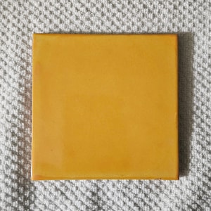 May include: A solid yellow square tile with a smooth, glossy finish.