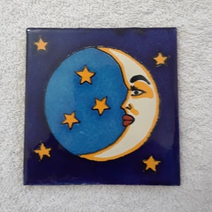 May include: A blue and white crescent moon with a face painted on it, surrounded by yellow stars on a dark blue background.