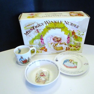 May include: A vintage Wedgwood Mrs. Tiggy-Winkle Nursery set. The set includes a box, a mug, a bowl, and a plate. The items feature illustrations of a hedgehog and a rabbit. The box has the words "Mrs. Tiggy-Winkle Nursery by Wedgwood" printed on it.