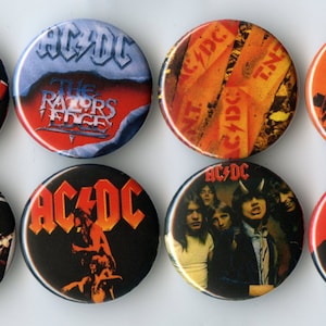 May include: A collection of eight round AC/DC band buttons. The buttons feature the band's logo, album art, and images of the band members. Colors include black, red, orange, and blue. These buttons are a great way to show your love for the band.