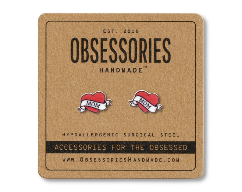 K&ouml;nnte beinhalten: Ohrstecker mit rotem Herzdesign und "MOM"-Banner. Auf einer braunen Karte mit dem Text "OBSESSORIES HANDMADE" und "ACCESSORIES FOR THE OBSESSED" pr&auml;sentiert.