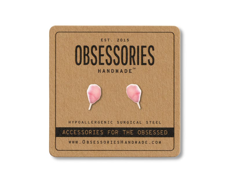 May include: A pair of pink petal-shaped earrings on a brown card. The card reads "OBSESSORIES HANDMADE" and "ACCESSORIES FOR THE OBSESSED". The earrings are made of hypoallergenic surgical steel.