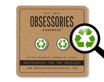 May include: A pair of silver stud earrings with a green recycle symbol on each. The earrings are on a brown card with the text "OBSESSORIES HANDMADE" and "ACCESSORIES FOR THE OBSESSED".