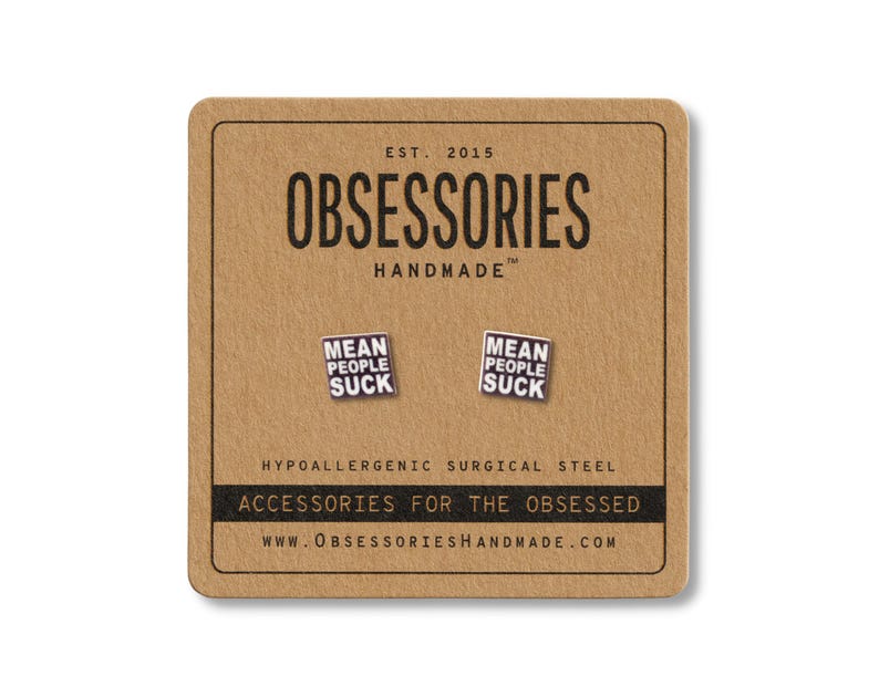 Op de afbeelding: Vierkante oorstekers met de tekst "MEAN PEOPLE SUCK" op een bruine kaart. De kaart toont "OBSESSORIES HANDMADE" en "ACCESSORIES FOR THE OBSESSED".