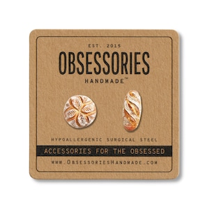 Może przedstawiać: Brązowa karta z napisem "OBSESSORIES HANDMADE" i dwiema kolczykami w kształcie chleba. Jeden kolczyk jest okrągły, drugi owalny. Karta zawiera r&oacute;wnież tekst "ACCESSORIES FOR THE OBSESSED" i "WWW.OBSESSORIESHANDMADE.COM".