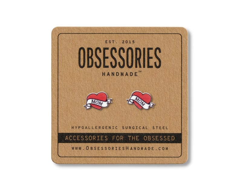 K&ouml;nnte beinhalten: Rote herzf&ouml;rmige Ohrstecker mit "MOM"-Banner auf einer braunen Karte. Die Karte tr&auml;gt den Text "OBSESSORIES HANDMADE" und "ACCESSORIES FOR THE OBSESSED".
